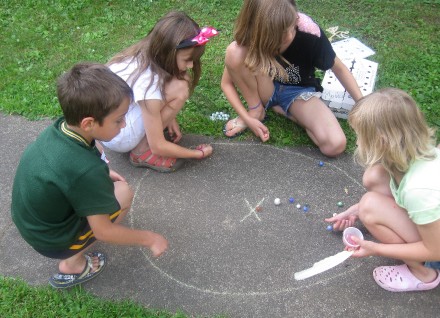 Kids learn how to play marbles